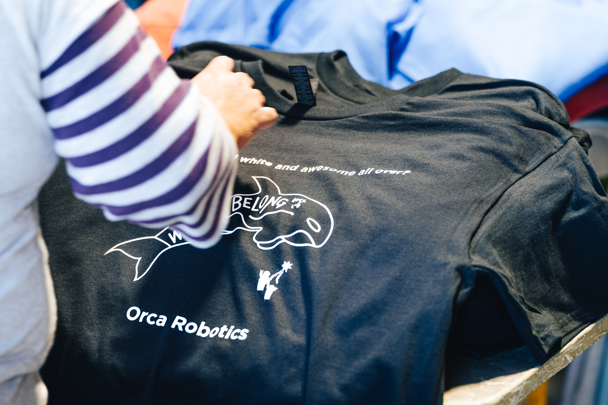 A Norwest Graphics employee inspecting a screen printed t-shirt for Orca Robotics as it comes off the production line